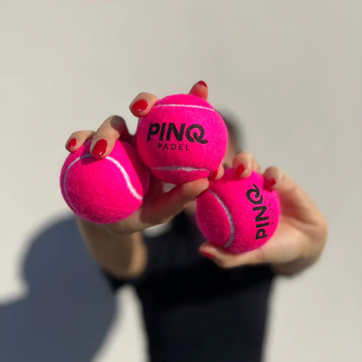 Pinq pink padel balls lifestyle image hand holding padel balls designed for all level players