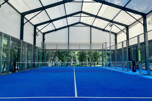 Indoor padel court viewed along the net with glass and cage structure, designed for all level players