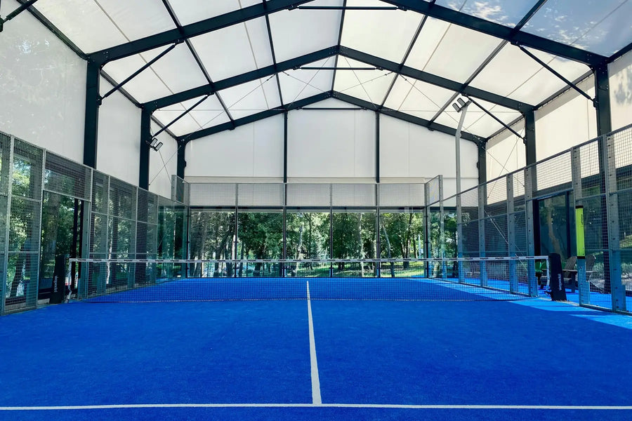 Indoor padel court viewed along the net with glass and cage structure, designed for all level players