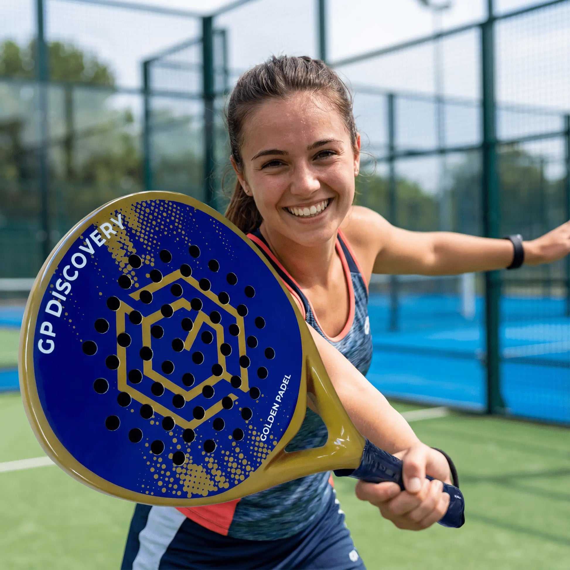 Female padel player holding GP Discovery padel racket at the net on outdoor court, designed for beginner players