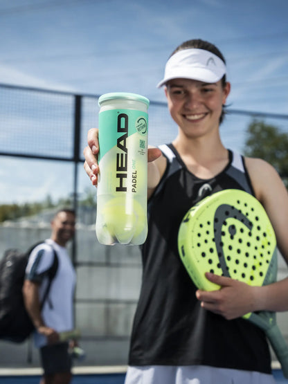 Head Padel One padel balls held by a player on an outdoor padel court showing sustainable tube design