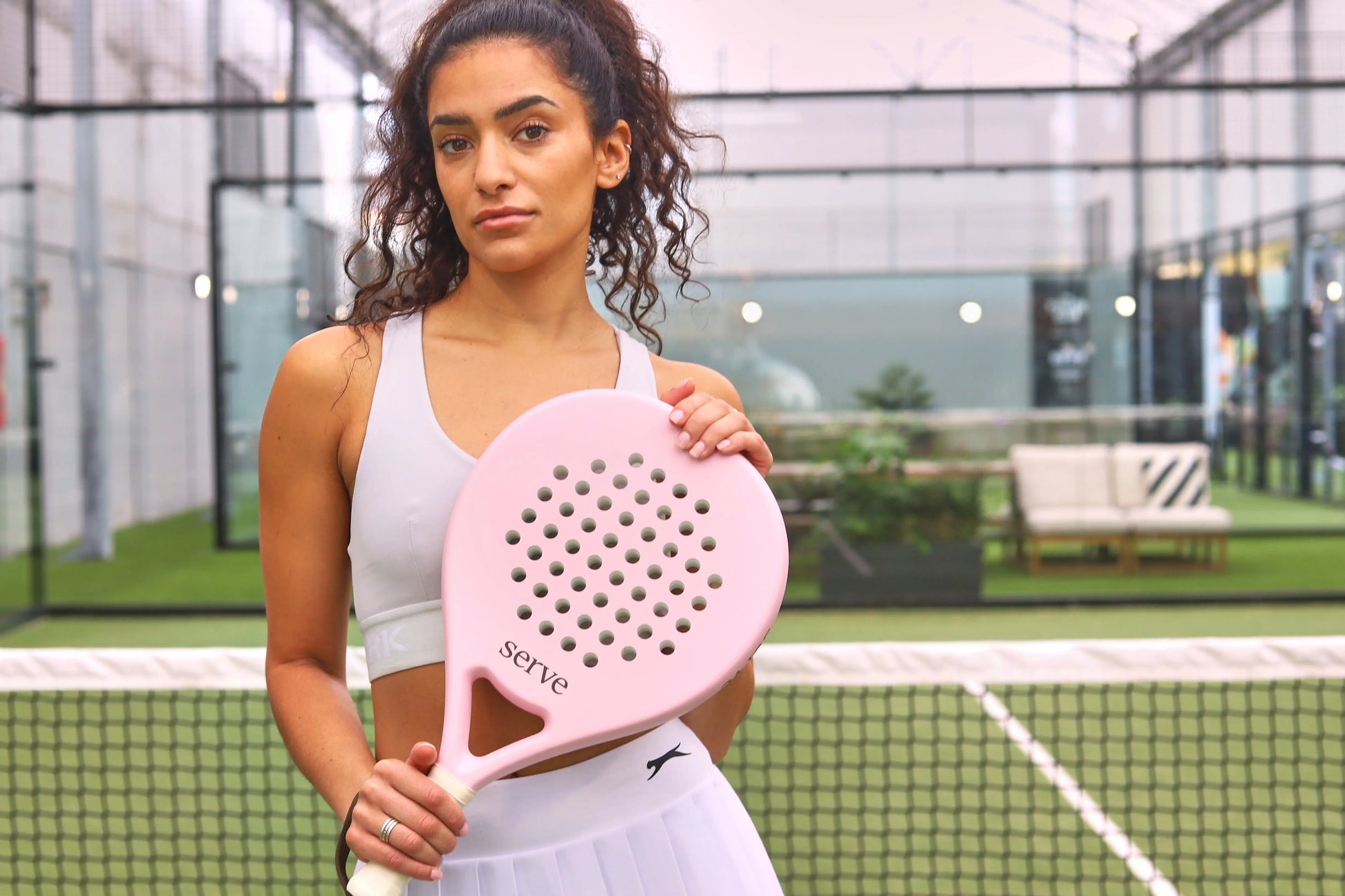 Woman holding Serve womens padel racket at the net on padel court, designed for women players.
