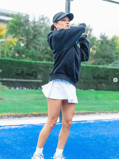 female padel player wearing Third Shot women’s performance skort in powder blue on padel court, designed for all level players