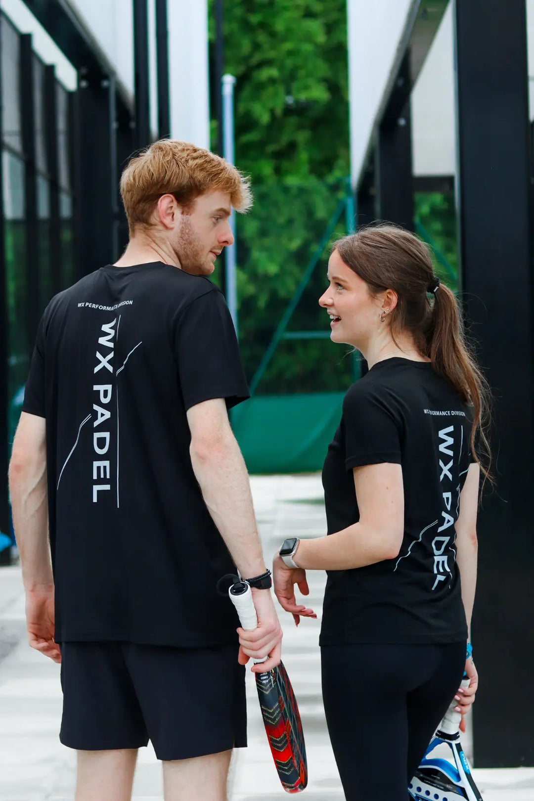 Male and female players wearing black WX Padel Performance Division T-Shirts showing the rear print
