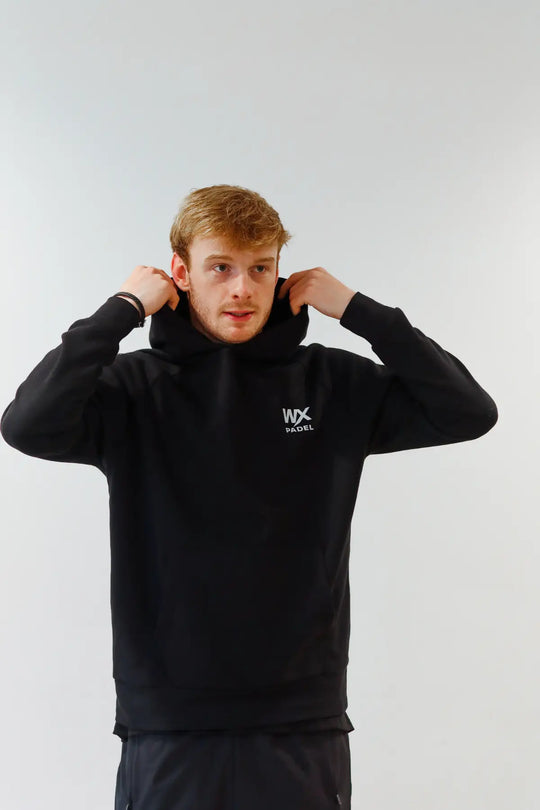 Male model wearing the WX Padel Pullover Hoodie in black with the hood raised
