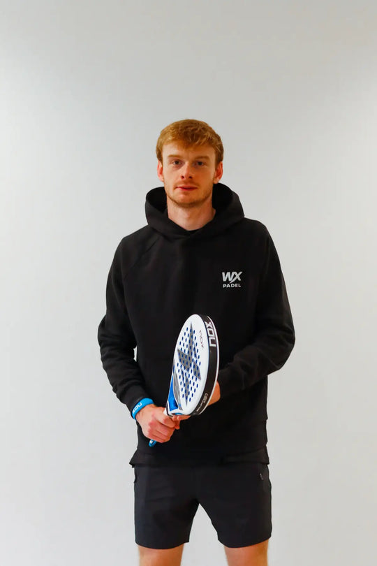 Male player wearing the WX Padel Pullover Hoodie in black holding a padel racket
